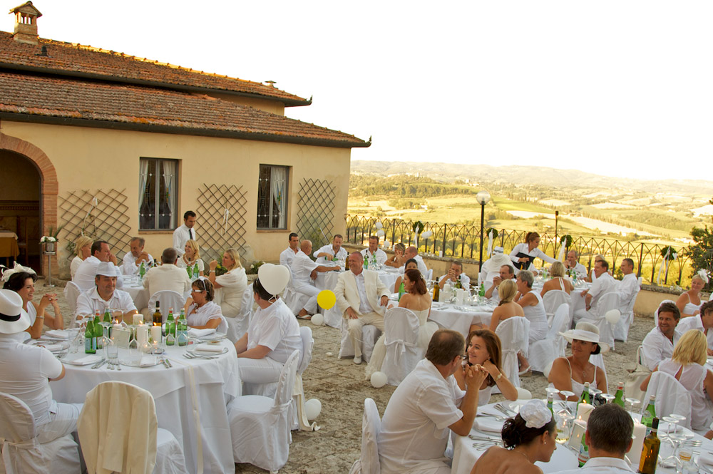 Ospiti vestiti di bianco a cena sulla terrazza della villa durante un evento estivo