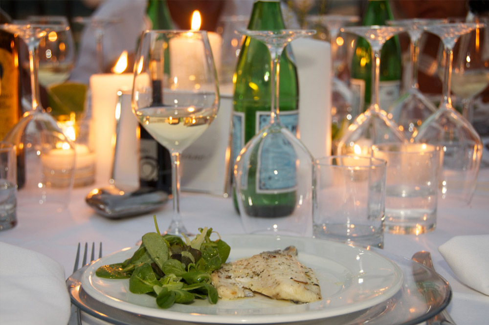 Filetto di pesce con insalatina servito su tavola apparecchiata a lume di candela