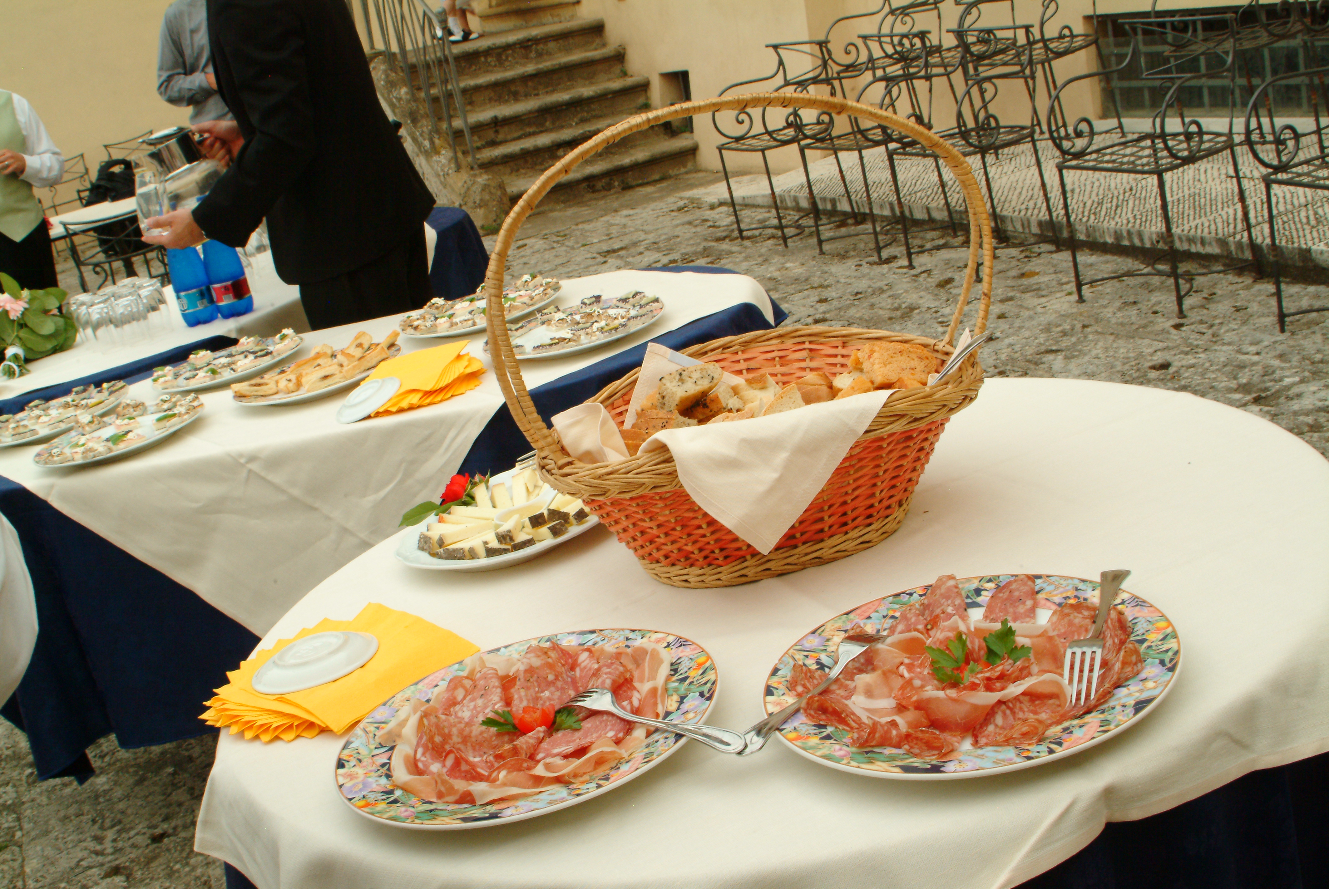 Tavolo da buffet nel cortile della villa con salumi, formaggi e cesto di pane