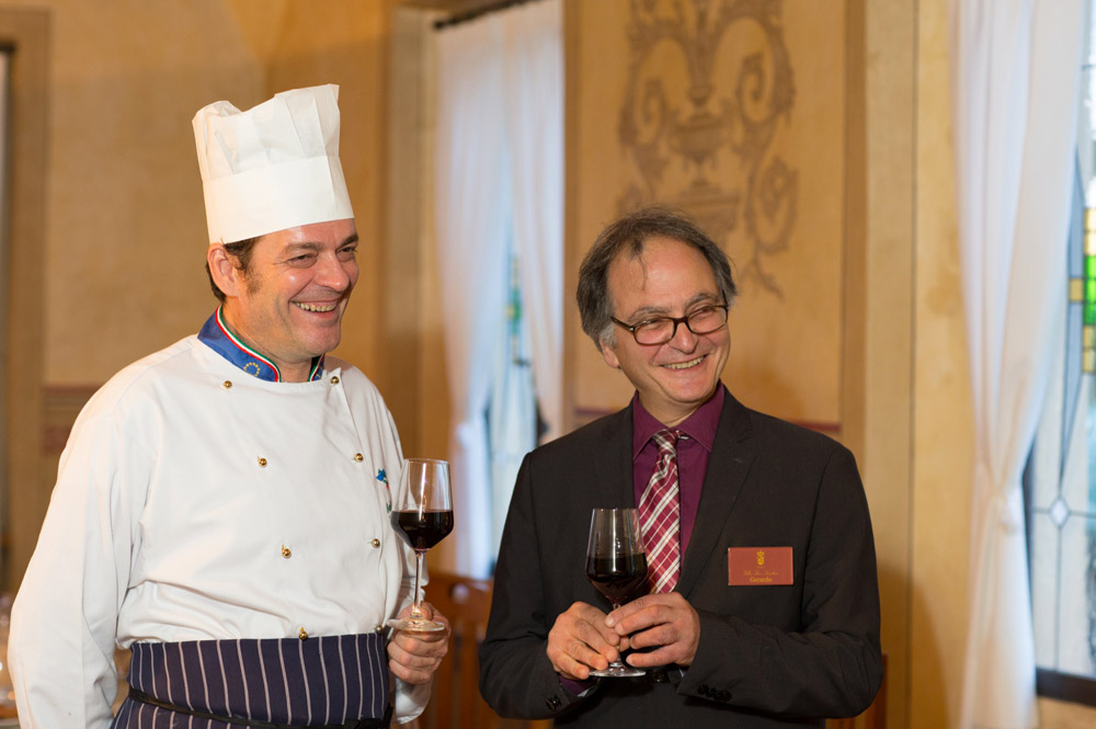 Lo chef e un responsabile di sala sorridenti con un calice di vino rosso