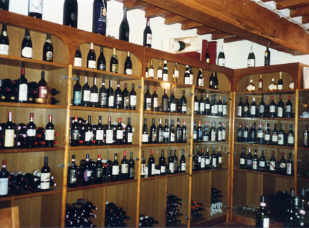 Scaffali in legno della cantina con bottiglie di vino toscano