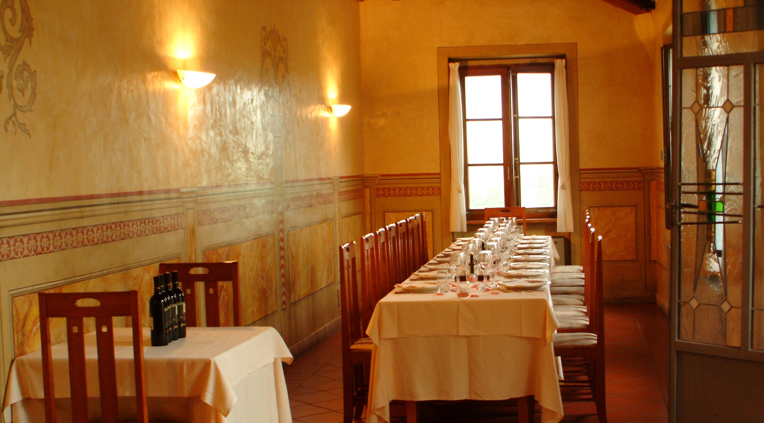 Sala interna del ristorante con pareti decorate e tavolo lungo apparecchiato